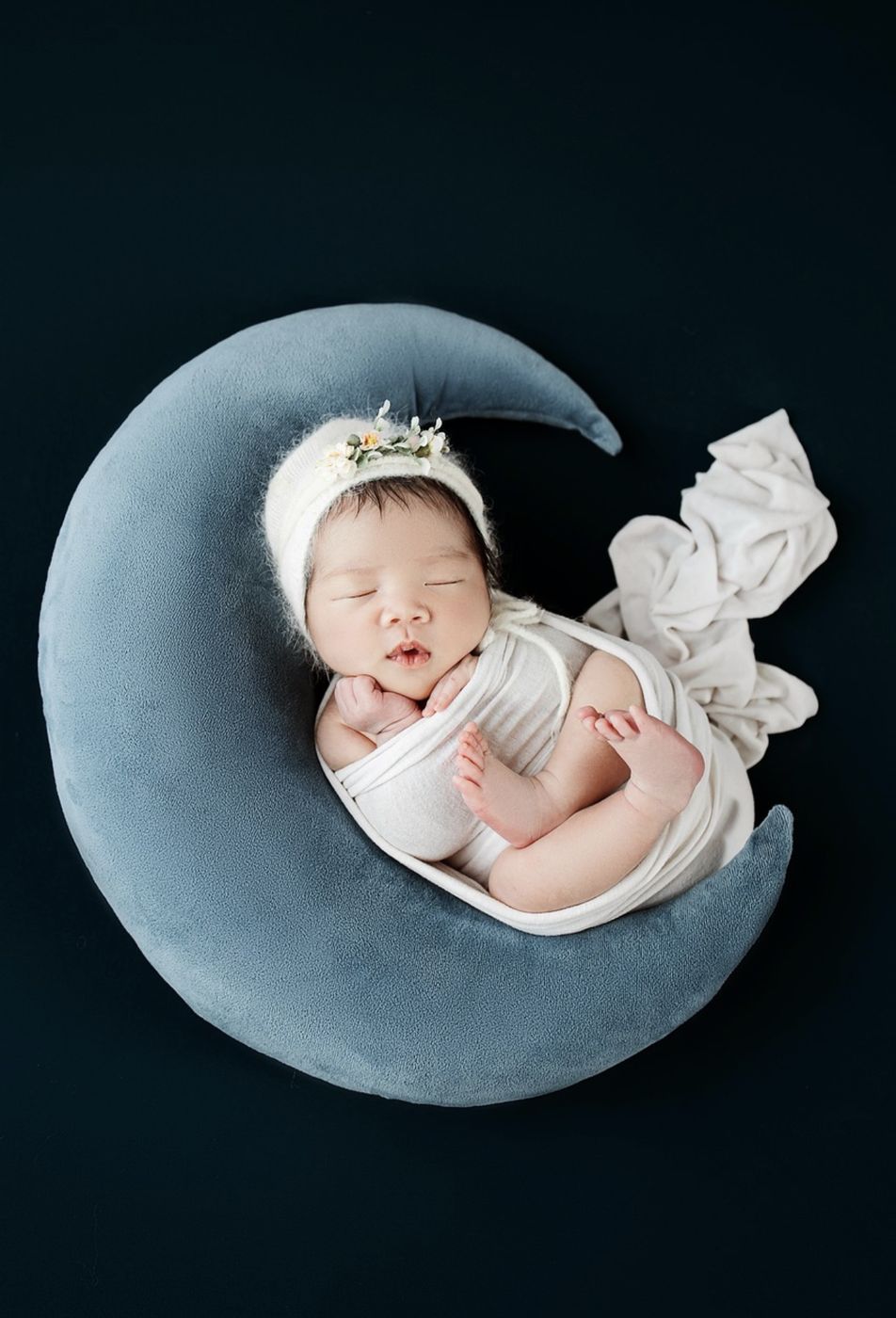 Newborn asleep on a crescent moon pillow