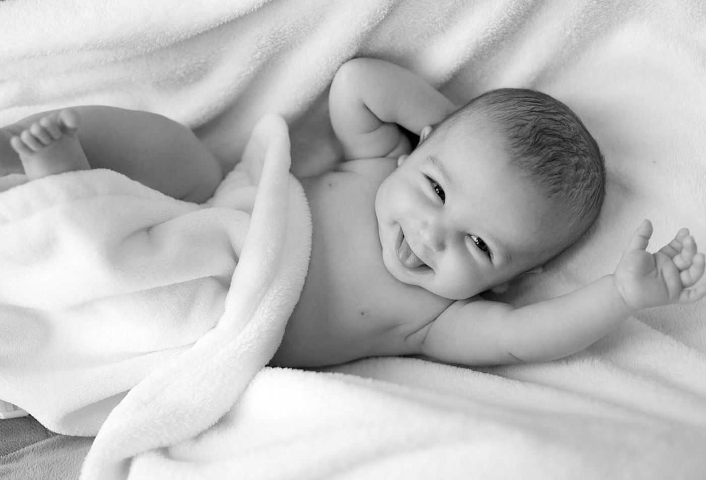 Smiling baby lying in a soft white blanket